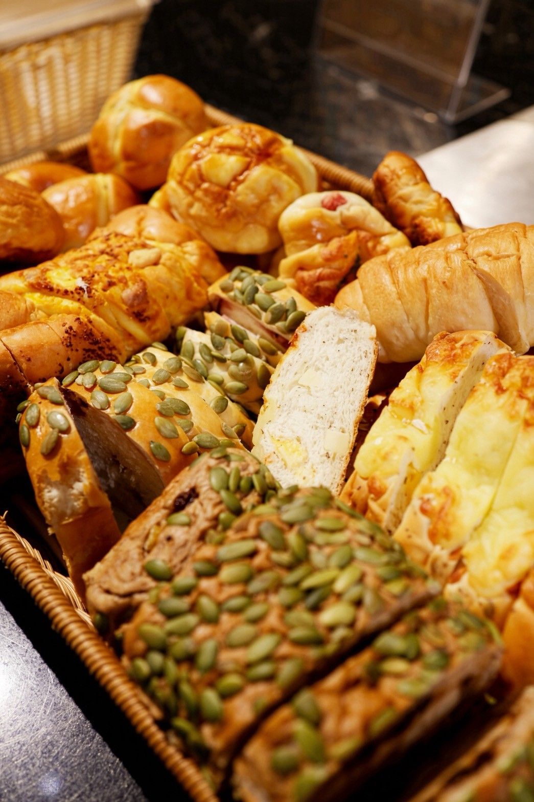 A variety of baked goods, including bread and pastries, displayed in a basket.