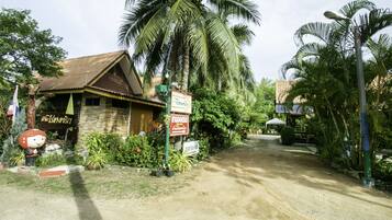 A rustic building with a signboard, surrounded by lush greenery and palm trees.