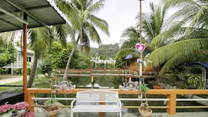 A covered seating area with a bench, potted plants, and a sign reading "Hotel". - OYO 1062 Baanrai Kongjaroen (Cha-am)