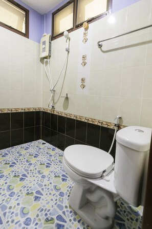 A bathroom with a toilet, a shower, and a hand dryer. - OYO 1062 Baanrai Kongjaroen (Cha-am)