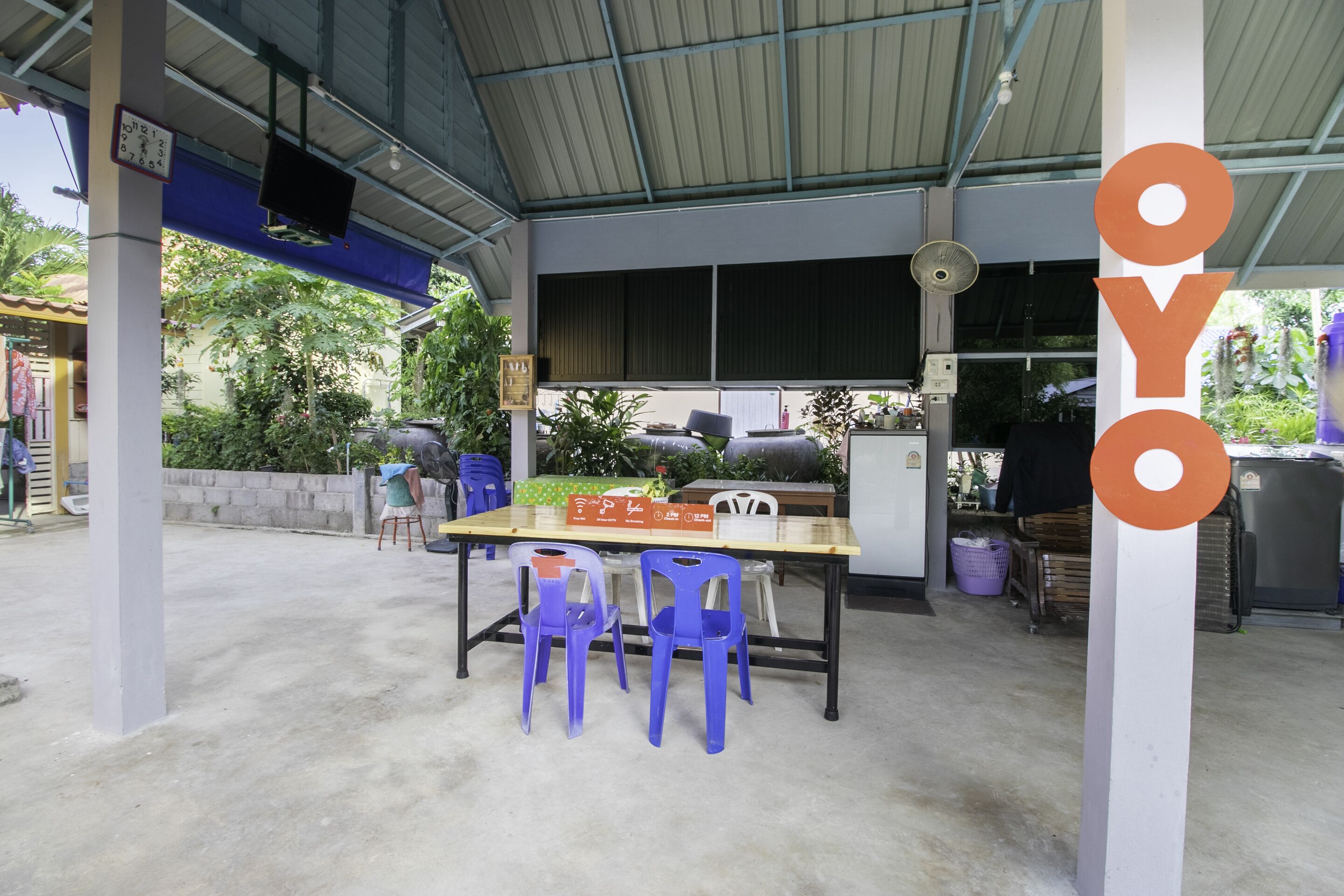 An outdoor covered area with a table and chairs, a clock, and a fan.