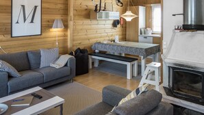 Een gezellig interieur van een vakantiehuisje met een zithoek, eethoek en een open haard.