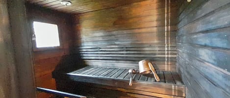 A cabin interior with a wooden bench, a window, and a metal railing.
