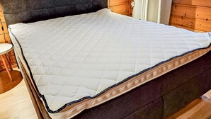 Een bed met een gewatteerd matras in een houten kamer.