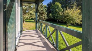 Eine überdachte Veranda mit Blick auf eine Rasenfläche und Bäume.