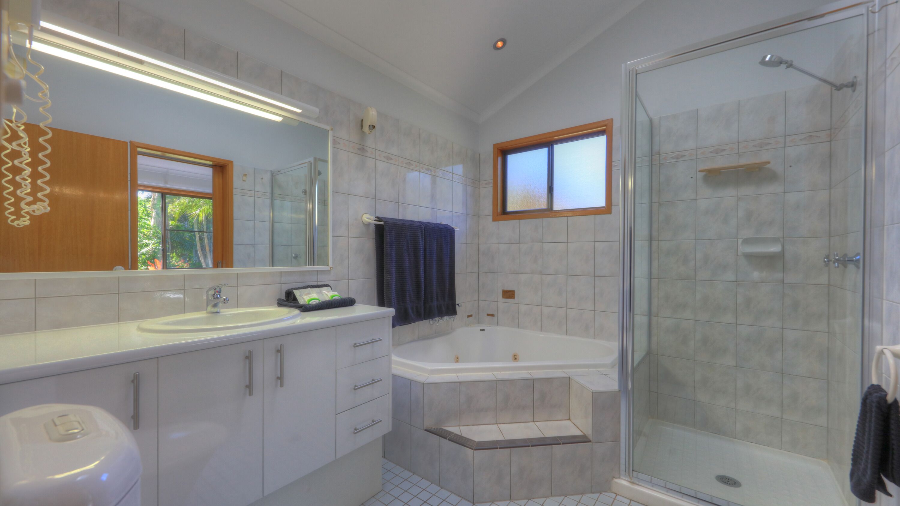 Un baño con un espejo grande, una bañera, una ducha y un lavamanos.
