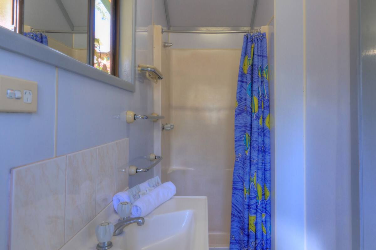 Une salle de bain avec un lavabo, un miroir et un rideau de douche.