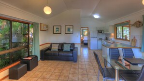 Una sala de estar moderna con un sofá, una mesa de comedor de vidrio y una cocina al fondo.