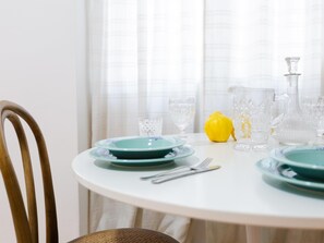 Une table de salle à manger ronde, avec des assiettes vertes, de la vaisselle transparente et un citron jaune.