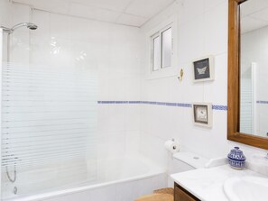 Une salle de bain comprenant une baignoire, des toilettes, un lavabo, une douche et un miroir.