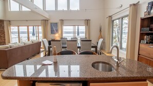 Una cocina moderna con encimeras de granito, un lavamanos integrado y un comedor con sillas y mesa.