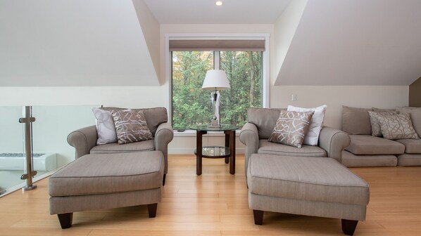 A modern living room with two sofas, a glass coffee table, and a lamp.