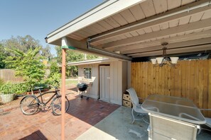 Un patio cubierto con una parrilla, una bicicleta y mobiliario exterior.
