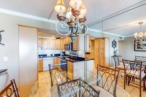 Enjoy cooking in the well-equipped kitchen with a central island and ample counter space, adjacent to a dining area with a glass table and metal chairs.