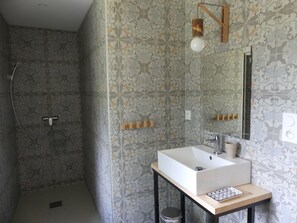 Bathroom features a large sink, mirror, and shower area with a showerhead and towel rack.