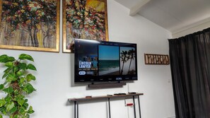 A flat-screen TV mounted on a wall with a framed painting above it.