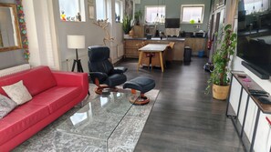 A modern living room with a red sofa, a glass coffee table, and a black leather chair.