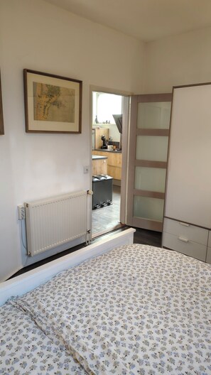 Um quarto com cama, radiador, guarda-roupa e um mapa na parede.