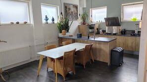 A modern kitchen with a central island, wooden cabinets, and a dining area with wicker chairs.