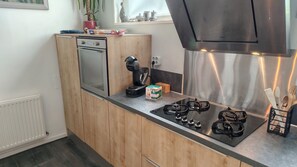 Una cocina moderna con armarios de madera, horno empotrado, cafetera y estufa a gas.