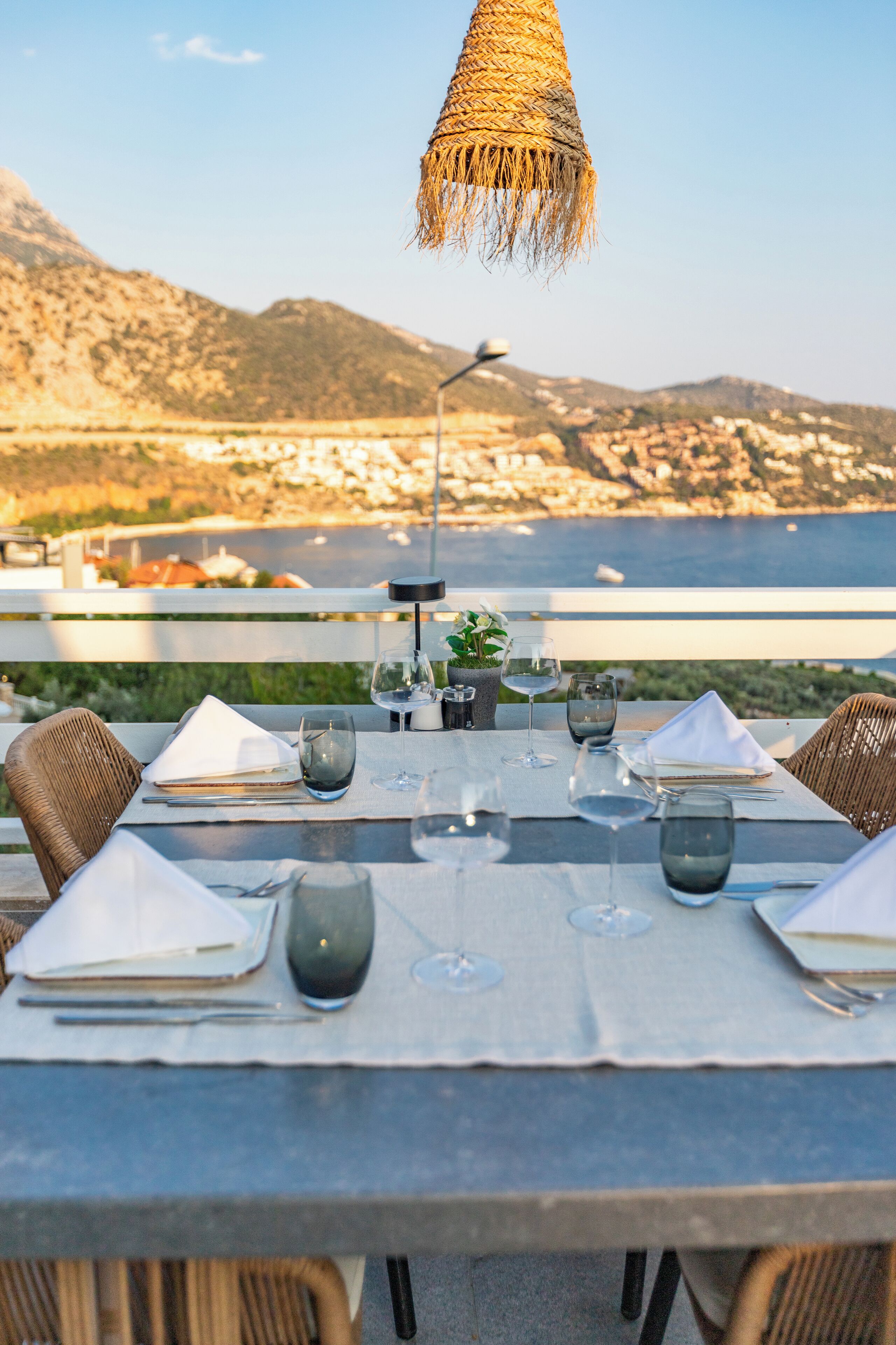 A table set for dining with a view of the sea and mountains in the background.