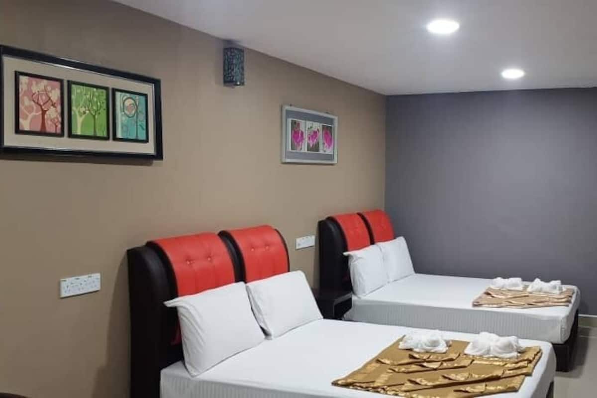 Une chambre d’hôtel avec deux lits, chacun doté d’une tête de lit rouge et blanche, et une petite table recouverte d’une nappe blanche.