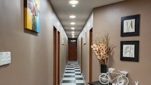 A hotel hallway with a checkered floor, a wall-mounted painting, and a table with decorative items. - New Wave Cyberjaya Hotel (Cyberjaya)
