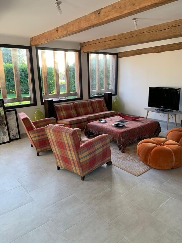 A living room with a sofa set, armchairs, a coffee table, and a television. - Renovated and decorated Norman wine press (Tourville-en-Auge)