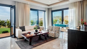 Un salon spacieux comprenant un canapé, des fauteuils, une table basse et donnant sur l’extérieur.