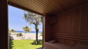 Un sauna avec des bancs en bois et une fenêtre donnant sur un espace verdoyant et la mer.