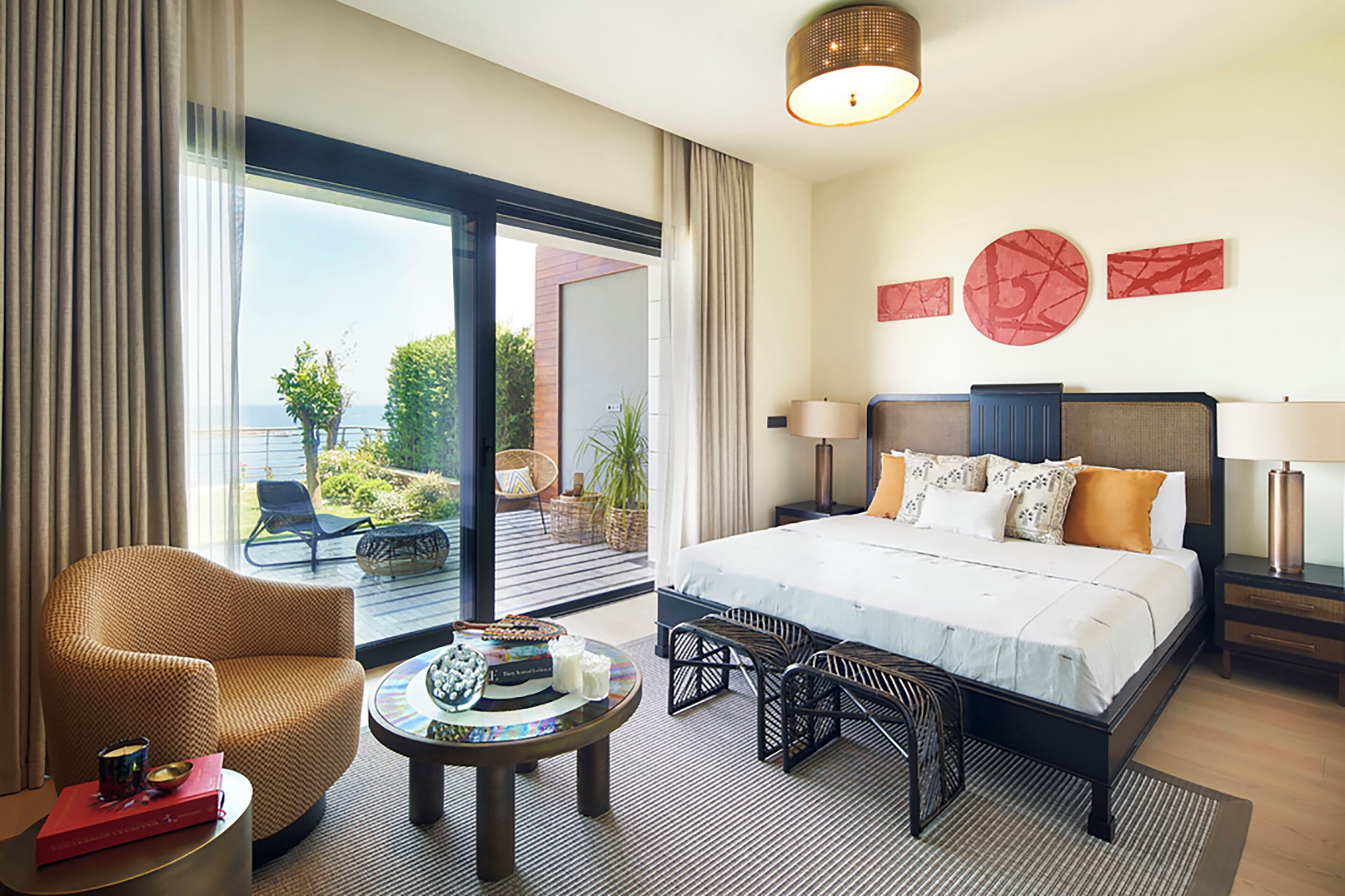 Habitación de hotel con una cama grande, una zona de estar con una silla y una mesa, y vistas al exterior.