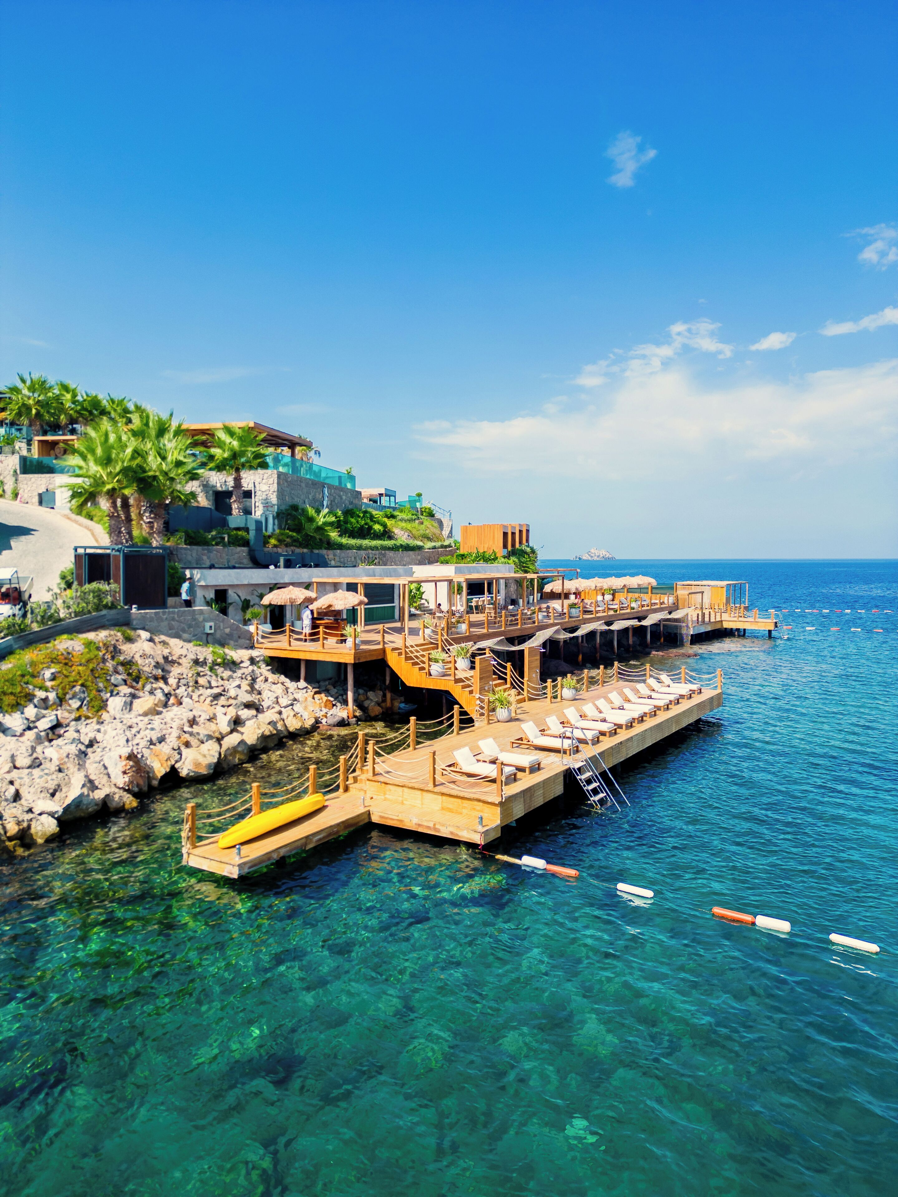 A waterfront property with a dock, clear water, and a view of the sea.