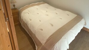 Une chambre à coucher avec un lit, un plancher en bois et une table de chevet avec une lampe.