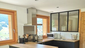Une cuisine moderne avec un plan de travail en bois, des meubles noirs et une grande fenêtre donnant sur l’extérieur.