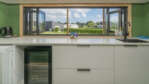 Eine moderne Küche mit großem Fenster, weißen Schränken und einem eingebauten Backofen.