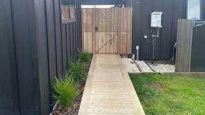 Ein modernes Gebäude mit einer Holzterrasse, die zu einem verschlossenen Eingang führt.