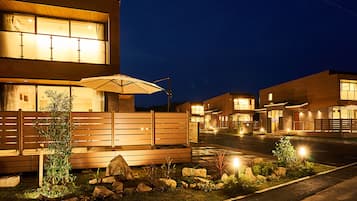 A modern residential building with multiple units, a well-lit entrance, and a landscaped garden area.