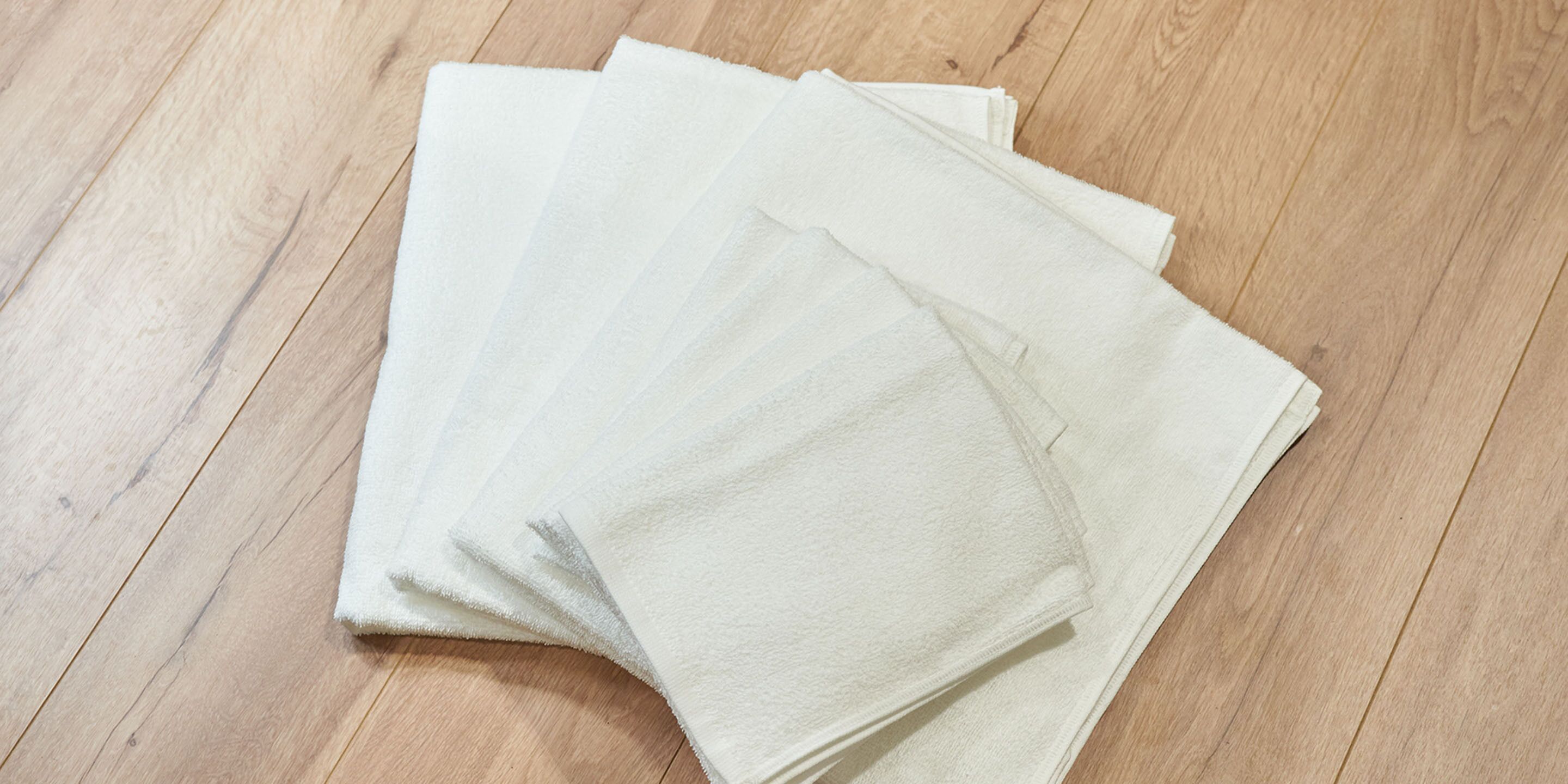 A stack of white towels on a wooden floor.