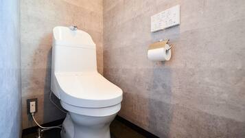 A modern toilet with a control panel, a toilet paper holder, and a wall-mounted sign.