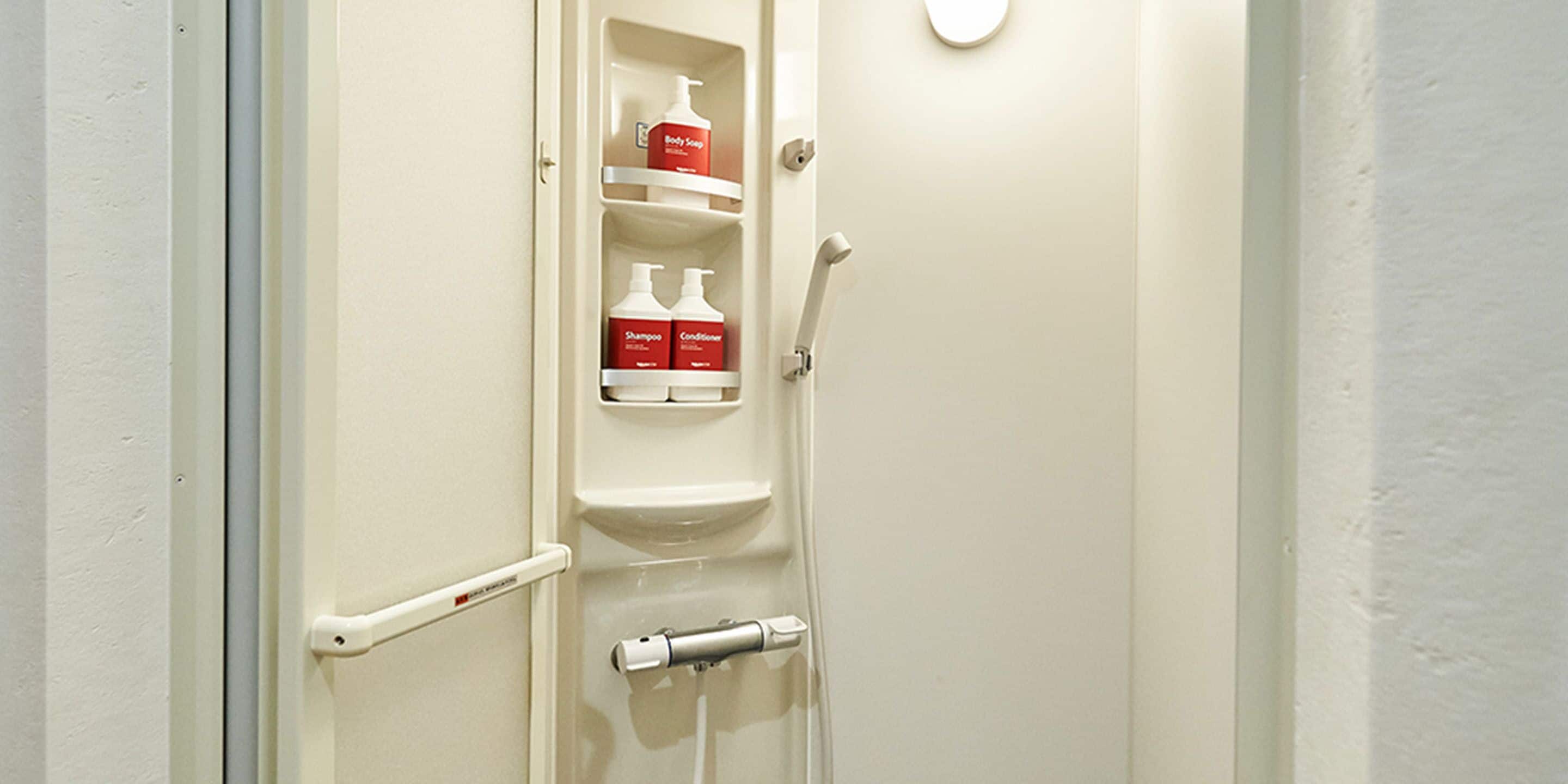 Un baño con puerta blanca, pasamanos y un estante con artículos de aseo.