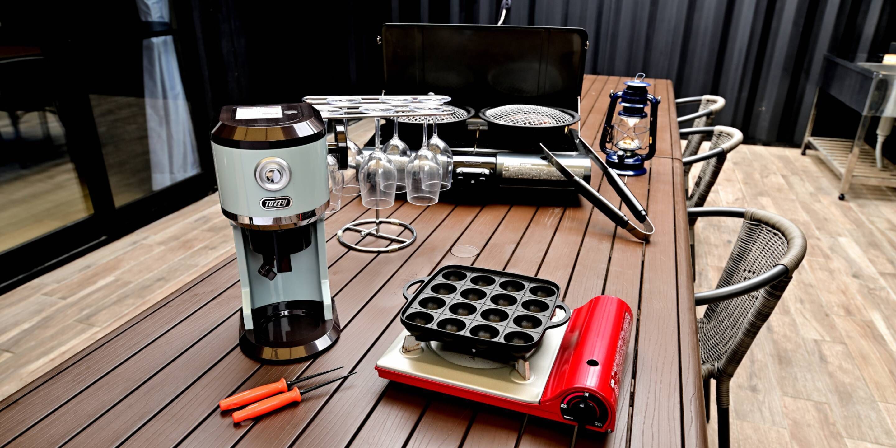 Une table sur laquelle se trouvent un appareil à gaufres, une machine à café et une plaque de cuisson portable.