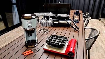 Une table sur laquelle se trouvent un appareil à gaufres, une machine à café et une plaque de cuisson portable.