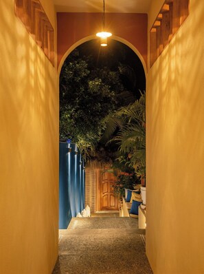 Un pasillo estrecho con una puerta de madera al final, que da a una habitación con vistas a árboles.