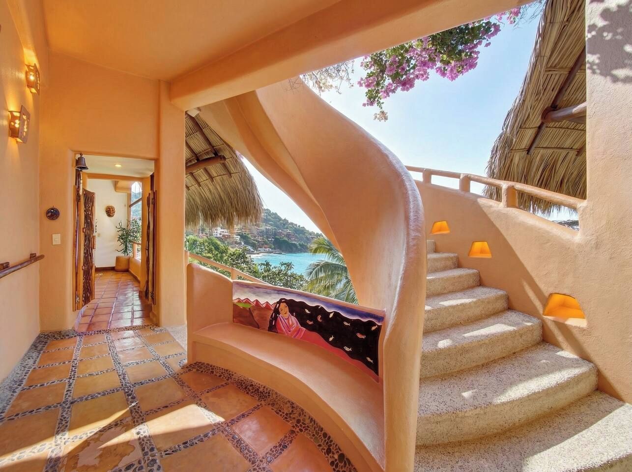A curved staircase with a view of the sea, a tiled floor, and a wall with a mural.
