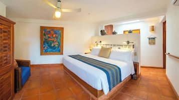 Ein Schlafzimmer mit einem Bett, einem Deckenventilator, einem Gemälde und einem gefliesten Boden.