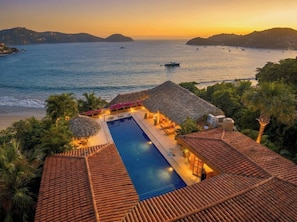 A resort with a swimming pool, thatched-roof structures, and a view of the sea. - Rarely Available- Casa Quixote - Beachfront Estate (Zihuatanjeo)