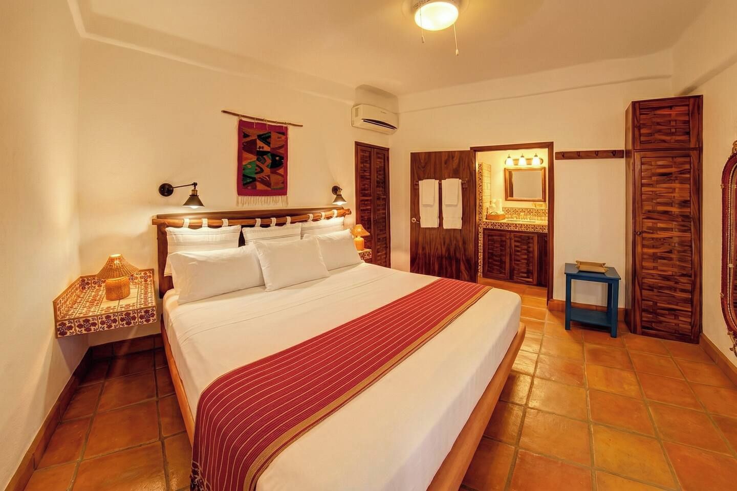 Une chambre d’hôtel avec un grand lit, une table de chevet, un miroir, une armoire et une petite table.
