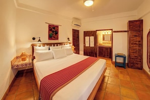 Une chambre d’hôtel avec un grand lit, une table de chevet, un miroir, une armoire et une petite table.
