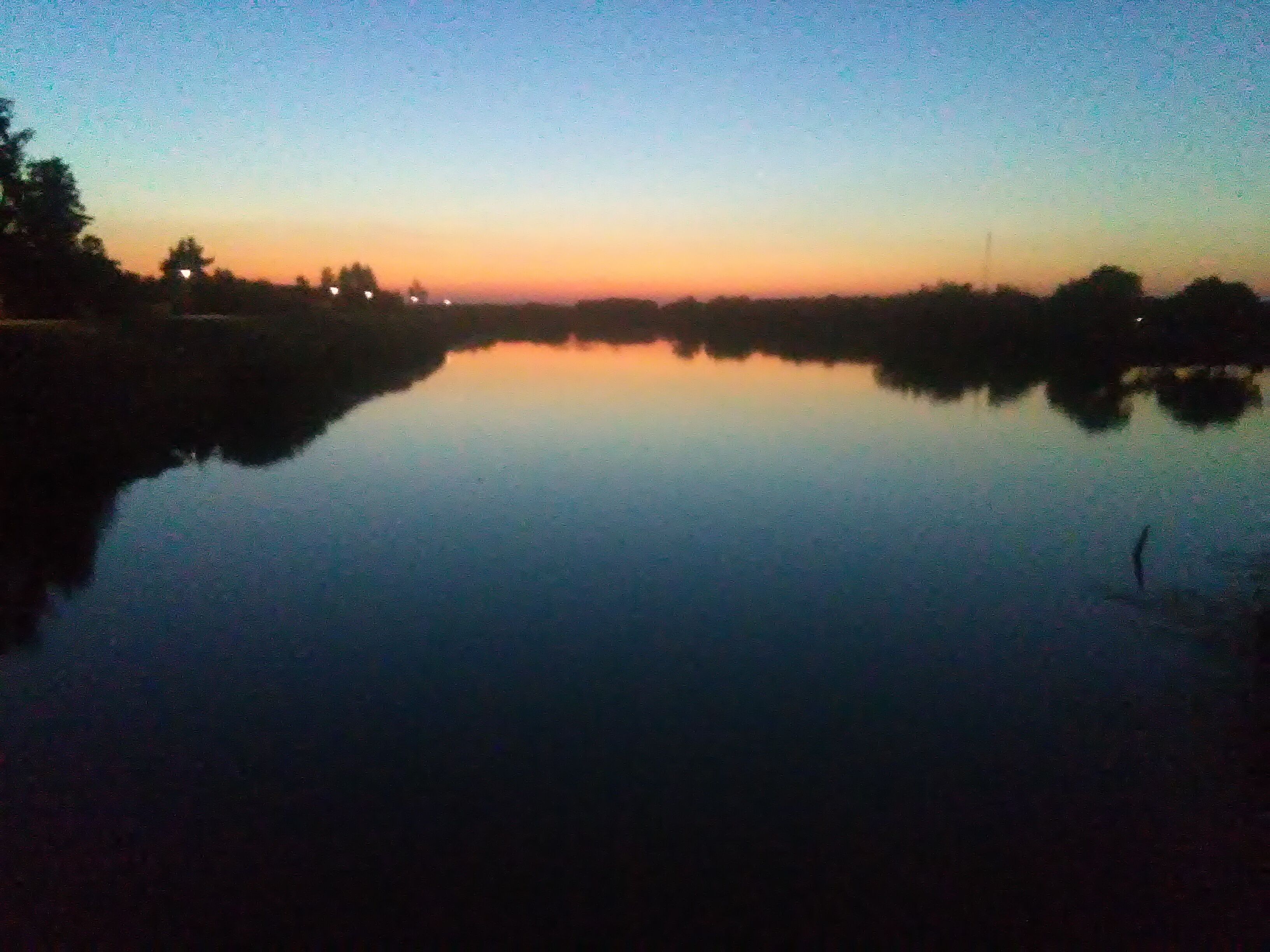 A calm body of water reflecting the sky during twilight.
