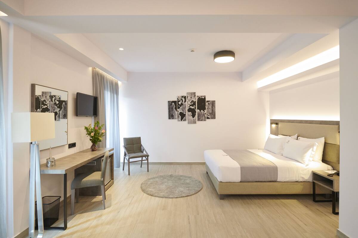 Ein modernes Hotelzimmer mit Bett, Schreibtisch, Stuhl und Kunstwerken an den Wänden.